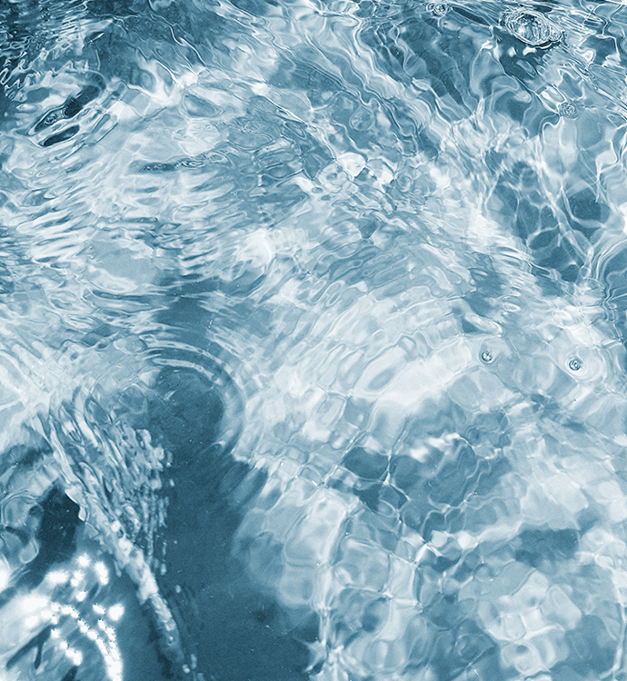 Ripples and light reflections on clear blue water, filling the frame with a textured, shimmering surface.