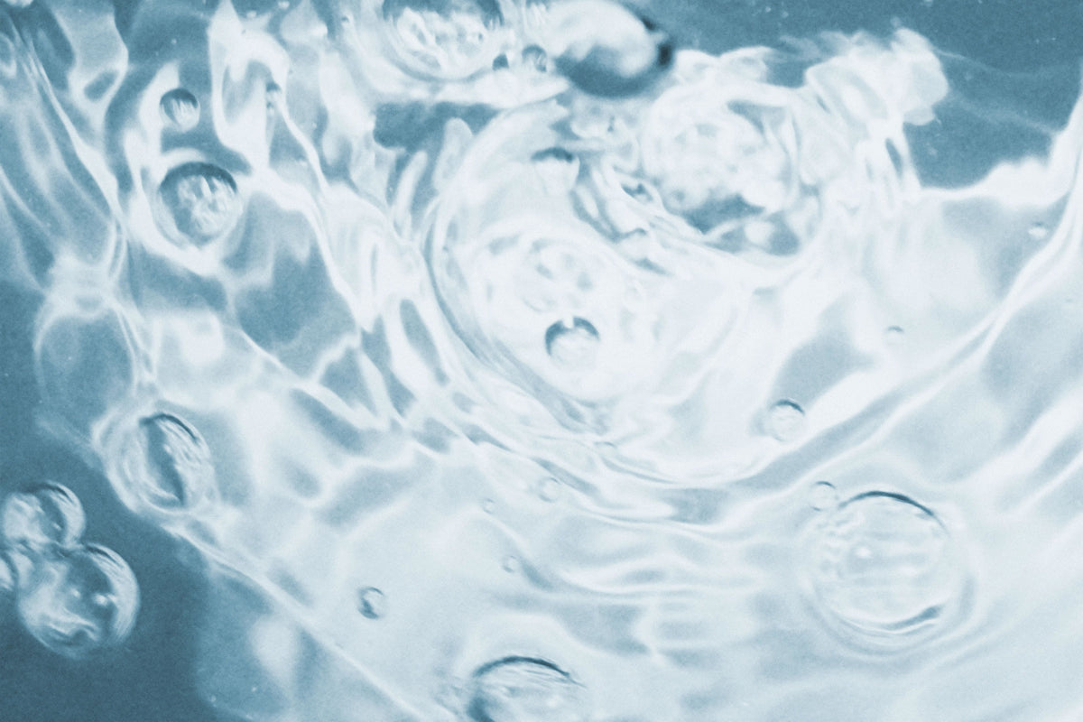 Abstract close-up of rippling water with translucent bubbles and cool blue-white tones.