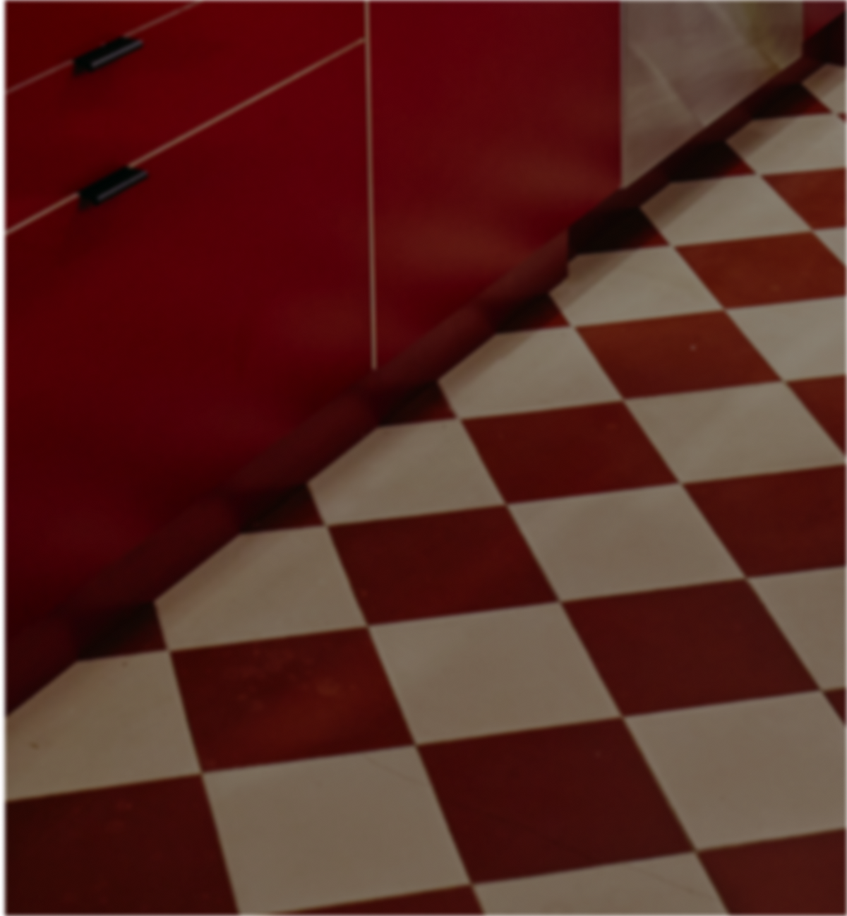 Red and white checkered floor tiles in a retro kitchen setting with a red cabinet visible on the left.