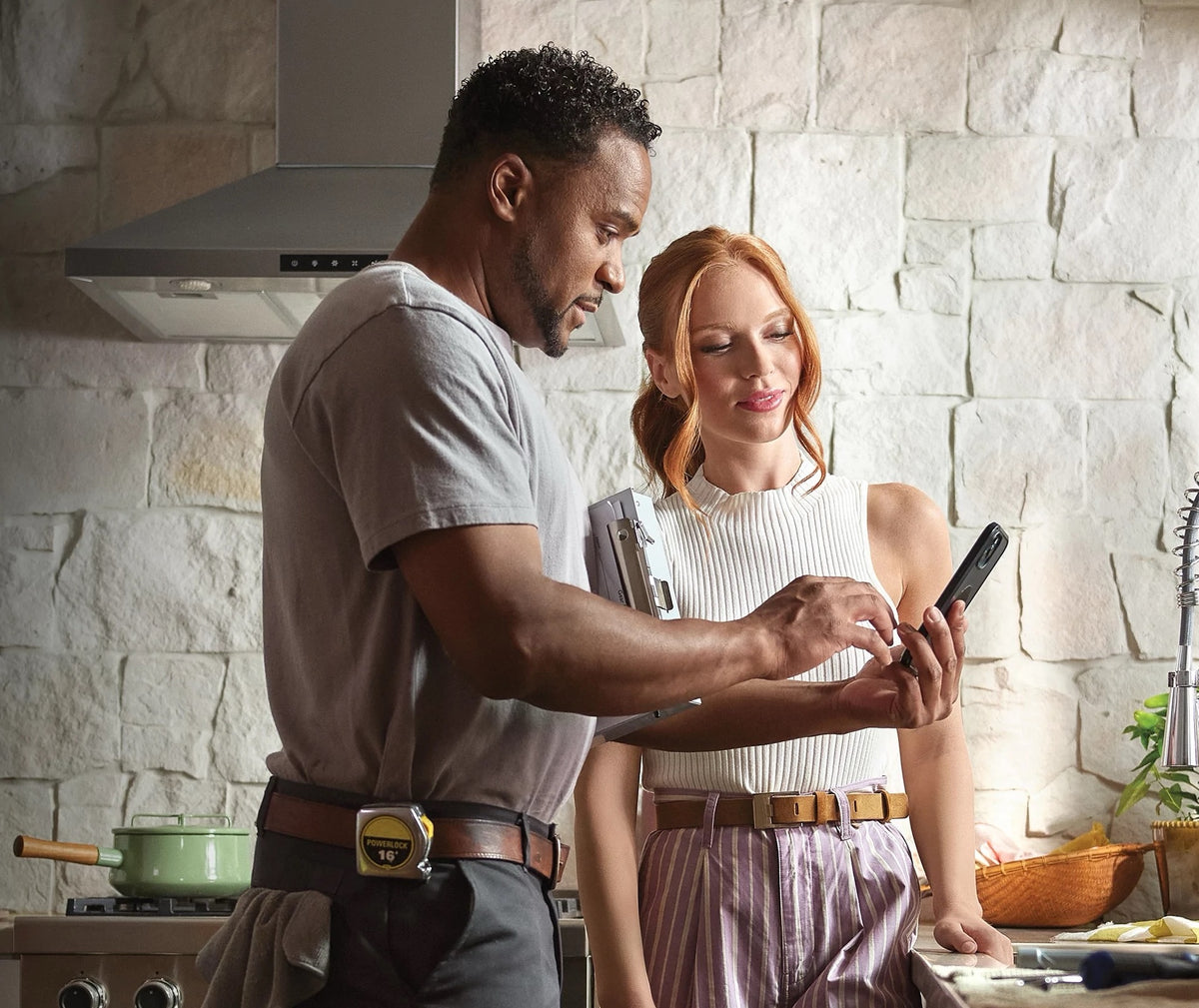 Handyman showing a woman an estimate on a phone in a kitchen 