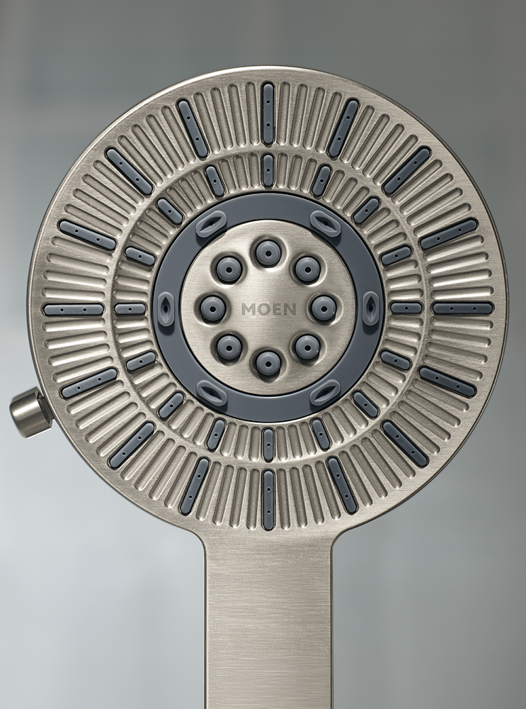 A close-up studio shot of a Moen shower head with a brushed nickel finish and dark gray accents, set against a neutral gray background.