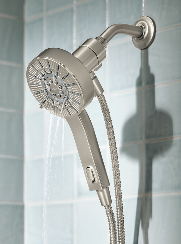 A modern wall-mounted shower head with a flexible hose, shown with water flowing from the spray head against a light blue tiled wall.