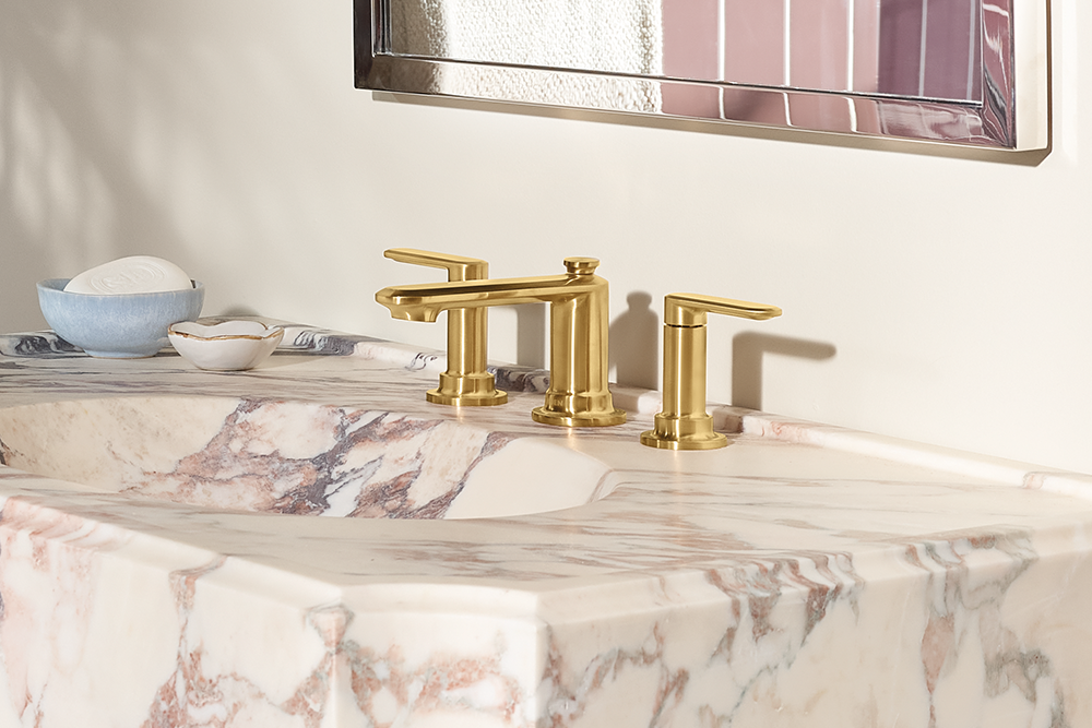 Greenfield Two-Handle Low Arc Bathroom Faucet mounted on a white and pink marble countertop, with a matching marble basin and a decorative mirror above.