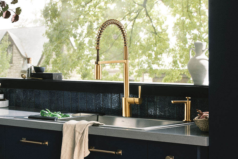 Align One-Handle Pre-Rinse Spring Pulldown Kitchen Faucet on a dark countertop with a dark tiled backsplash, set in front of a window with green foliage visible outside.